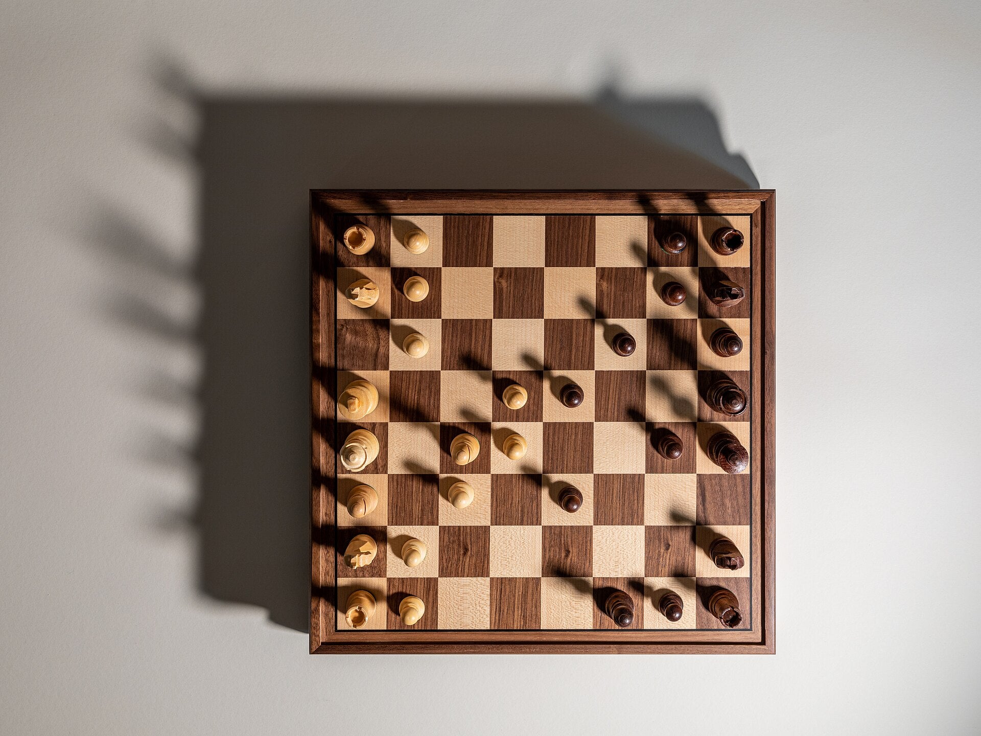 Wooden chess board seen from above, pieces set up for a game