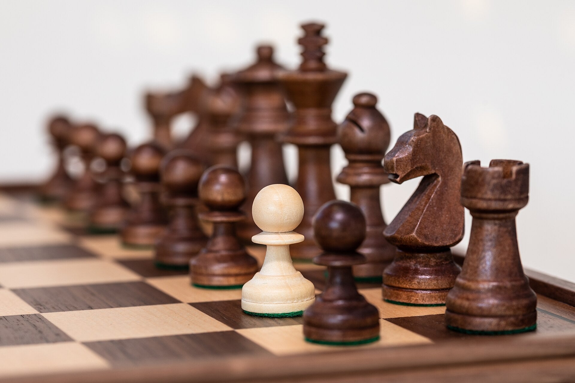 Dark Staunton chess pieces with a knight in the foreground
